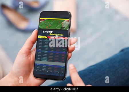 Donna che scommette sullo sport usando lo smartphone, primo piano. Sito Web bookmaker in mostra Foto Stock