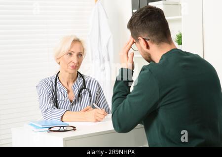 Medico che consulta il paziente al tavolo bianco della clinica Foto Stock