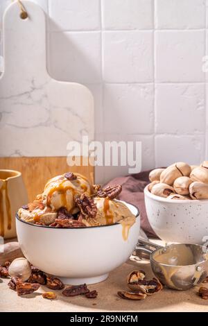Ciotola per gelato alla torta di pecan. Tradizionale gelato alla torta di caramello pecan piccante autunnale, con ricca salsa al caramello e molte noci, su spaghetti da tavola Foto Stock