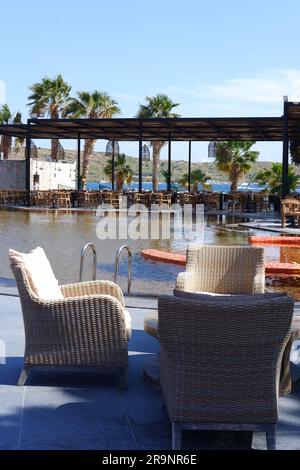 Tavoli e sedie in legno a bordo piscina in un hotel Foto Stock