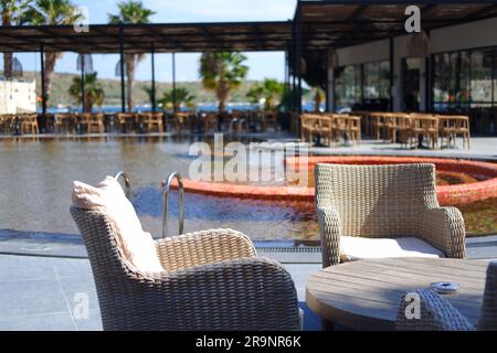 Tavoli e sedie in legno a bordo piscina in un hotel Foto Stock