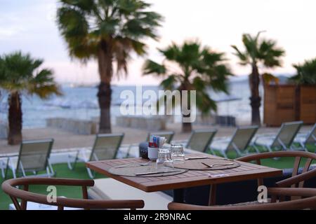 Tavoli e sedie in legno a bordo piscina in un hotel Foto Stock