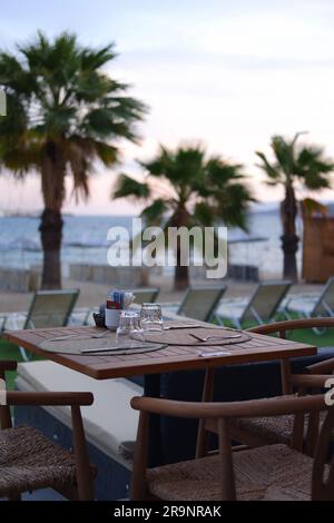 Tavoli e sedie in legno a bordo piscina in un hotel Foto Stock