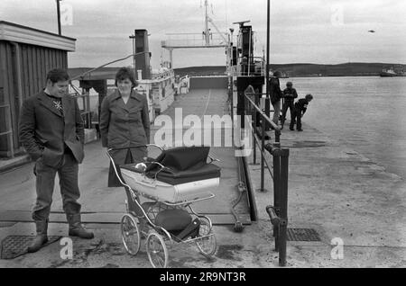 Coppia con il bambino in carrozza, aspettando il traghetto per Bressay. Lerwick, Shetlands Mainland, Shetland Islands, Scozia, circa 1979. REGNO UNITO 1970S HOMER SYKES Foto Stock