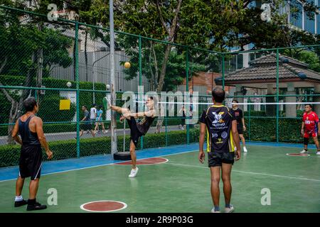 I giocatori thailandesi di Sepak Takraw, spesso composti da lavoratori o tassisti a motore alla fine della giornata, sono visti giocare una partita al Benchasiri Public Park sulla Sukhumvit Road. Sepak Takraw chiamato anche kick volley o pallavolo acrobatico della Thailandia è uno degli sport più popolari del sud-est asiatico che si gioca con una palla fatta di rattan o plastica sintetica dove i giocatori possono solo toccare la palla con i piedi, il corpo o la testa. Foto Stock