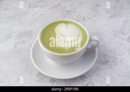 Cappuccino al pistacchio modellato in una tazza bianca su sfondo bianco Foto Stock