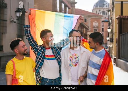 Nel caldo bagliore del tramonto di una vivace città, quattro amici gay condividono uno stretto legame, celebrando il loro vivace cameratismo in mezzo a un mare di orgoglio LGBT ador Foto Stock