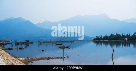 Foto che si affaccia su una laguna con barche ancorate e montagne sullo sfondo. Foto Stock