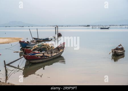 Una foto che guarda le piccole barche ancorate in una laguna vietnamita. Foto Stock