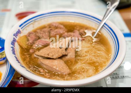 Una ciotola di deliziosi spaghetti di riso con fegato di maiale e maiale in un ristorante per il tè di Hong Kong Foto Stock