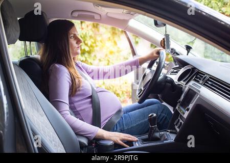 Una donna incinta che indossa la cintura di sicurezza guida un'auto.  Sicurezza e guida durante la gravidanza, il viaggio Foto stock - Alamy