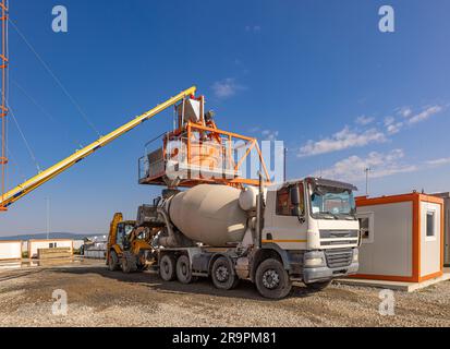 Camion per calcestruzzo pesante in cantiere. Processo di produzione del calcestruzzo nella costruzione moderna Foto Stock