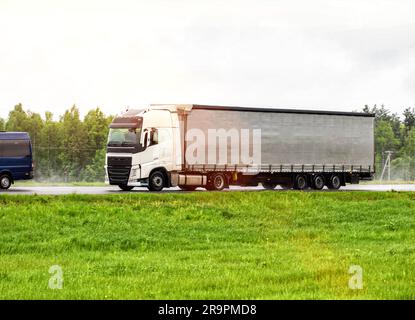 Un autocarro ribaltabile trasporta il carico su un'autostrada in caso di pioggia su una strada sdrucciolevole. Il concetto di sostituzione delle importazioni Foto Stock