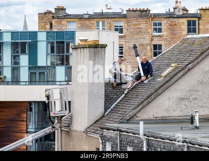 Operai nel raccoglitore ciliegie che sostituisce la bocchetta del tetto, Leith, Edimburgo, Scozia, Regno Unito Foto Stock