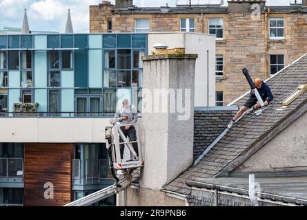 Operai nel raccoglitore ciliegie che sostituisce la bocchetta del tetto, Leith, Edimburgo, Scozia, Regno Unito Foto Stock