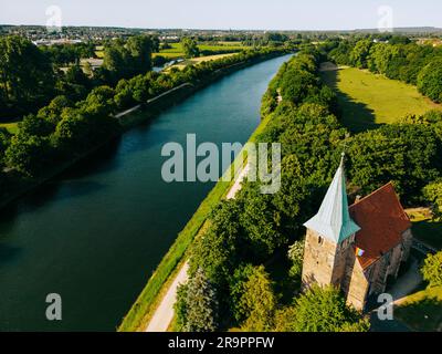 D'estate, vista aerea con droni, fiume navigabile con ponti, campi agricoli e foreste e case contadine nella campagna tedesca. Foto Stock