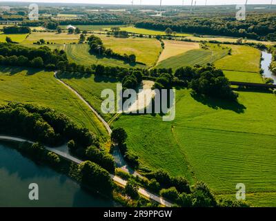 D'estate, vista aerea con droni, fiume navigabile con ponti, campi agricoli e foreste e case contadine nella campagna tedesca. Foto Stock