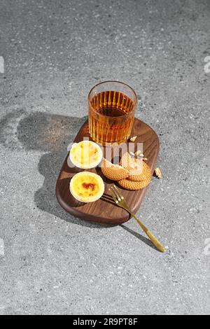 Una tavola di legno con dolci freschi e un bicchiere di tè sulla superficie di cemento Foto Stock