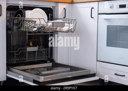 Molti piatti sporchi in lavastoviglie. Aiutare la padrona di casa, l'economia e l'ecologia. Pulizia in cucina Foto Stock