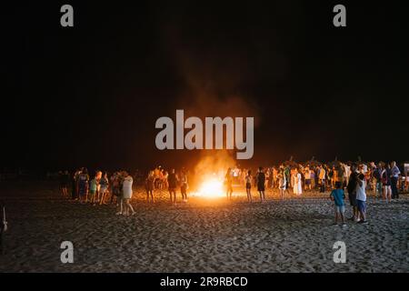 Malaga, Spagna - 24 giugno 2023: Gente intorno al falò sulla spiaggia per il famoso festival del giorno di San Juan nel solstizio d'estate. Foto Stock