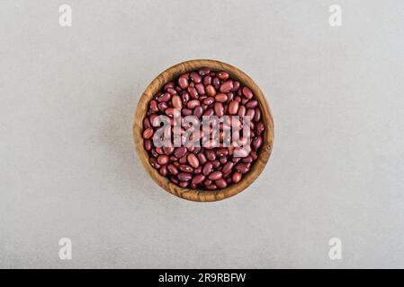 Essiccare i fagioli rossi biologici crudi in un recipiente di legno su fondo di cemento. Vista dall'alto Foto Stock