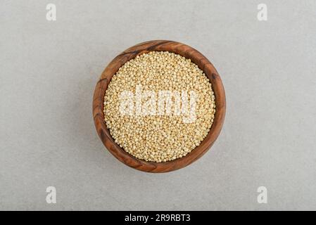 Quinoa bianca cruda in un recipiente di legno su fondo di cemento. Vista dall'alto Foto Stock