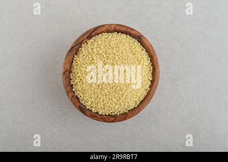 Couscous crudo in un recipiente di legno su fondo di cemento. Vista dall'alto Foto Stock