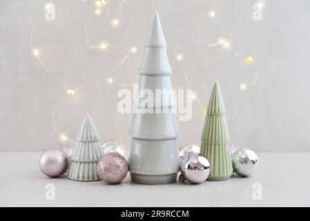 Abeti decorativi in ceramica con palline di natale e ramoscelli di abete su sfondo chiaro Foto Stock