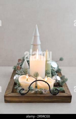 Abeti decorativi in ceramica con palline di natale blu e candele su vassoio di legno su sfondo di legno scuro Foto Stock