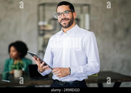 Ritratto del giovane uomo d'affari mediorientale con tablet in ufficio Foto Stock