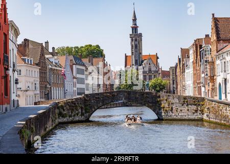 Ponte di pietra sul canale Langerei a Bruges, con una barca turistica che passa sotto il ponte, Brugge, Belgio Foto Stock