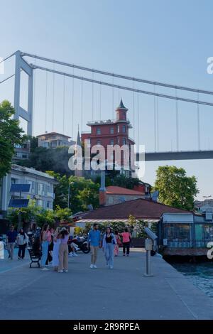 La gente cammina sul lungomare di Rumeli con il Fatih Sultan Mehmet Bridge, noto anche come secondo ponte sul Bosforo, alle spalle, Istanbul, Turchia Foto Stock