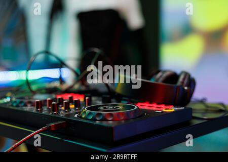 Controller DJ con rotelline, manopole e pulsanti per mixare musica elettronica sul palco del nightclub. Pannello console Musician e cuffie per spettacoli dal vivo in discoteca Foto Stock