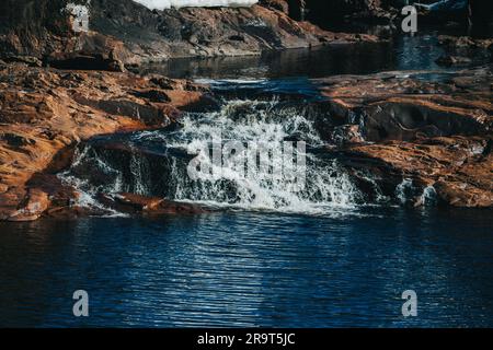Una piccola cascata che scorre attraverso un paesaggio naturale in Svezia Foto Stock
