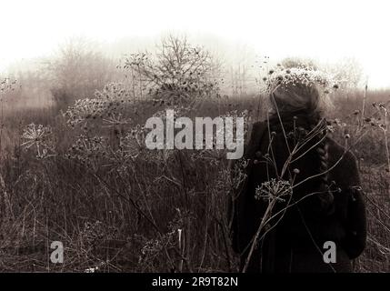 Strega verde che cammina attraverso paludi innevate. Immagine stratificata con colori creativi. Foto Stock