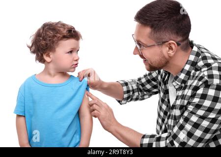 Padre che applica l'unguento sulla spalla del figlio su sfondo bianco Foto Stock