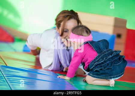Bella bambina di dieci mesi che gioca con la mamma. Concetto di stimolazione precoce per i bambini piccoli. Foto Stock