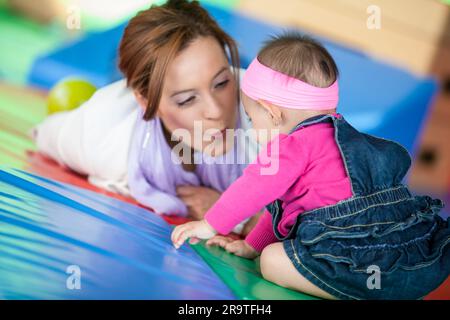 Bella bambina di dieci mesi che gioca con la mamma. Concetto di stimolazione precoce per i bambini piccoli. Foto Stock