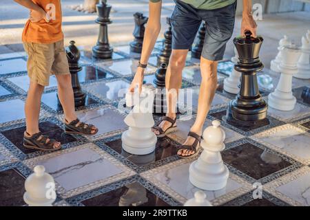 Padre e figlio giocano a scacchi e trascorrono del tempo insieme all'aperto. I bambini giocano a scacchi Foto Stock