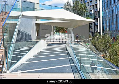 Un paio di persone e una persona camminano sul Tide, una strada pedonale rialzata e lineare e parte del parco di una sezione lunga 1 km, North Greenwich, Londra, Regno Unito Foto Stock