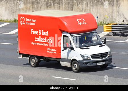 Logo della British Heart Foundation davanti a furgoni e autista della collezione di beneficenza rossa e bianca che viaggia lungo la strada orbitale M25 nell'Essex, Inghilterra, Regno Unito Foto Stock