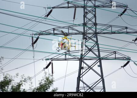 Elicottero Airbus giallo vicino a linee elettriche troppo alte Foto Stock