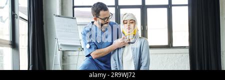 operatore sanitario professionale in occhiali e uniforme mettendo il sostegno del collo su donna asiatica con testa bendata, situazioni di emergenza concetto di risposta, Foto Stock