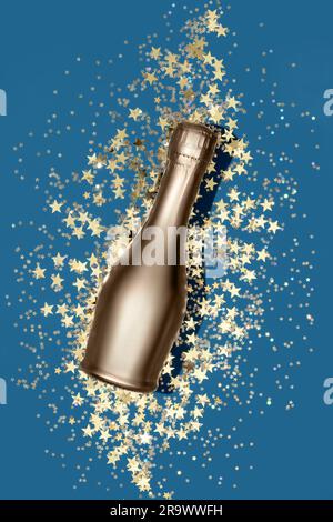 Composizione di lusso con bottiglia di champagne dorata e coriandoli a forma di stella dorata su sfondo blu in stile piatto. Concetto di festa di Natale o Capodanno. Foto Stock