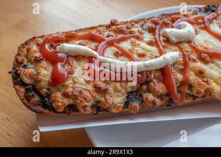 scopri il gusto della polonia con un appetitoso zapiekanka, un panino caldo su mezza baguette, abbondantemente riempito con vari condimenti, che offre una Foto Stock