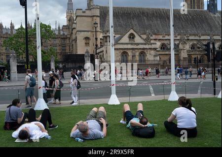 Parliament Square, Londra. 24 giugno 2023. I turisti si rilassano sull'erba di fronte alla camera dei comuni. Foto Stock