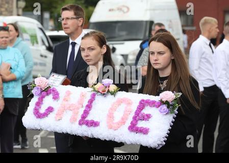 Le sorelle di Chloe Mitchell, Kirsty (a sinistra) e Nadine, portano una corona davanti alla sua bara mentre viene portata lungo Larne Street, a Ballymena. Data foto: Giovedì 29 giugno 2023. Foto Stock