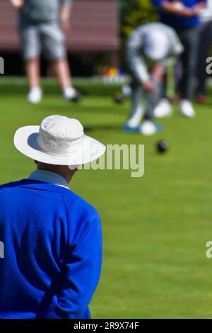 Giocatore di bocce con cappello bianco che guarda un altro giocatore lanciare Un Bowl, Inghilterra Regno Unito Foto Stock