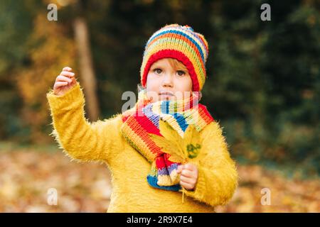 Ritratto all'aperto di una graziosa bambina che indossa un pullover giallo, che gioca nel parco autunnale Foto Stock