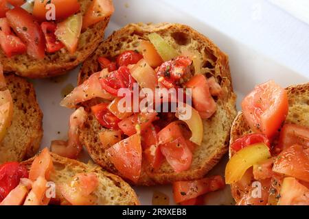 Friselle pugliese, tipica cucina estiva pugliese, Italia meridionale. Ciambelle croccanti a base di farina di grano duro condite con pomodori e olio d'oliva Foto Stock